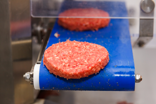 burger meat on conveyor belt